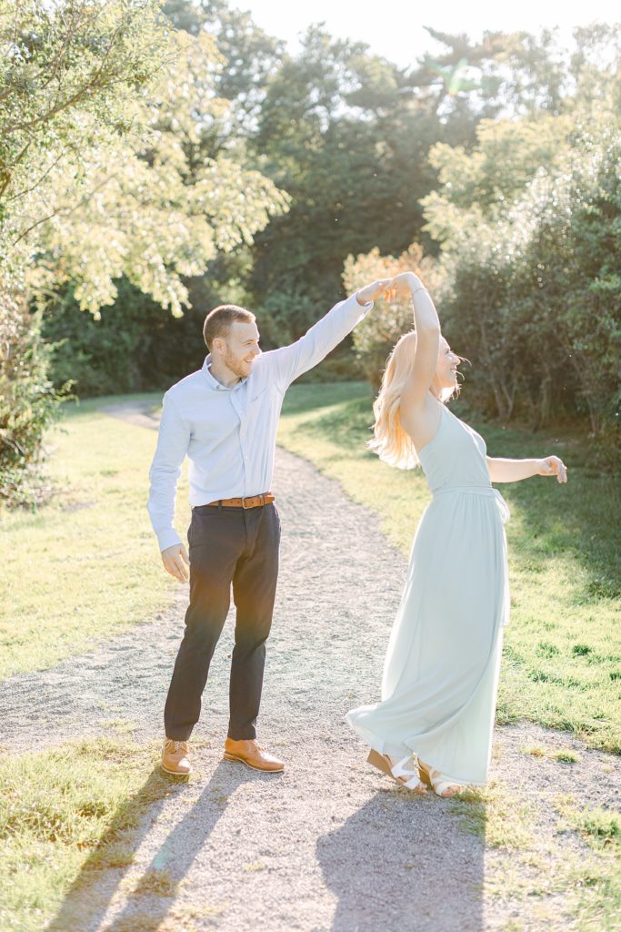 A man twirls a woman while they take their formal engagement photos