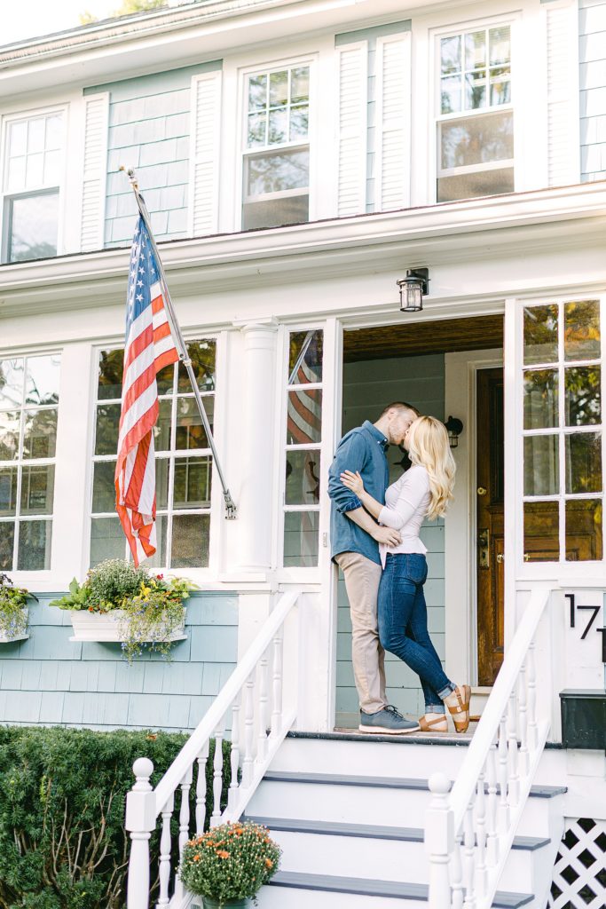 Front porch engagement photo with the couple kissing