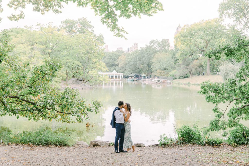 NYC engagement photos with a couple kissing in front of the pond